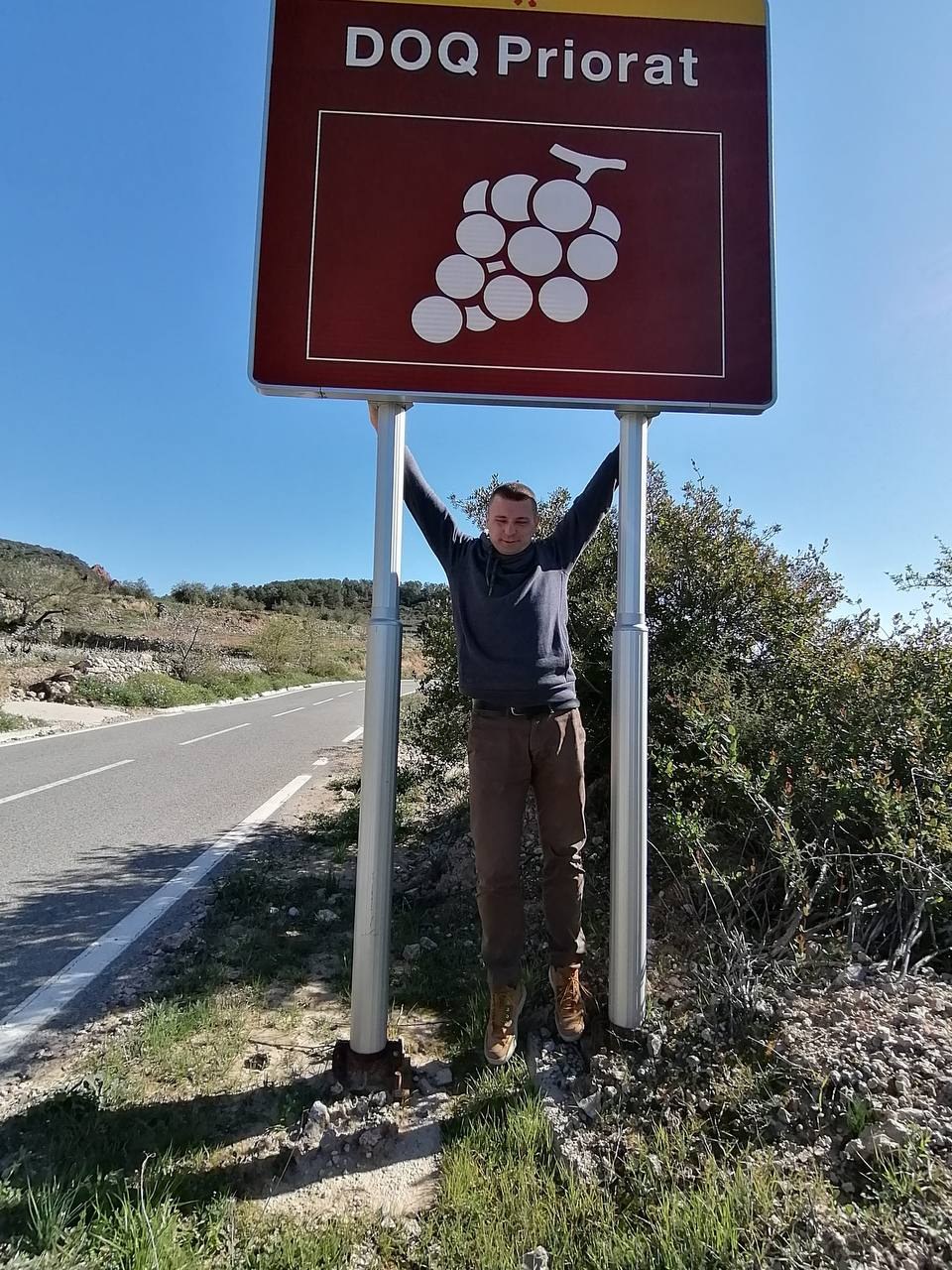 Сомелье Александр Кульбачко у дорожного знака DOQ Priorat в Каталонии